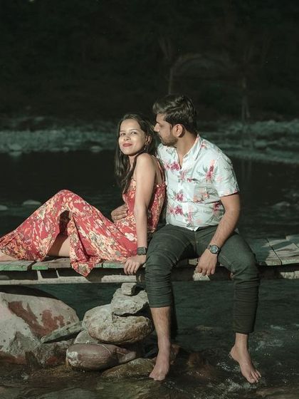 A romantic nighttime shot of the couple sitting on a wooden plank over the river, showcasing our ability to shoot in various lighting conditions.