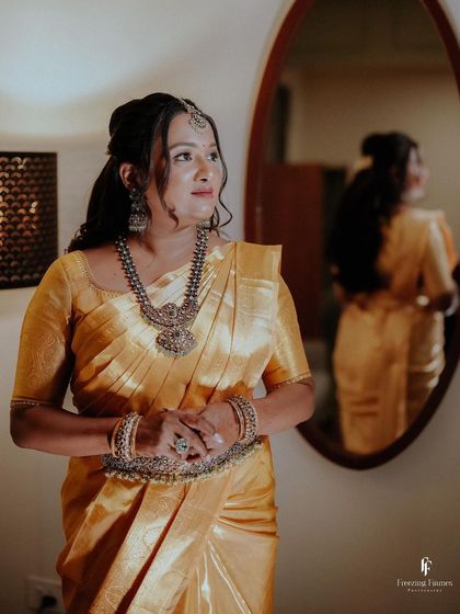 A portrait of the bride in her yellow silk saree, capturing a moment of quiet reflection before the engagement ceremony begins.