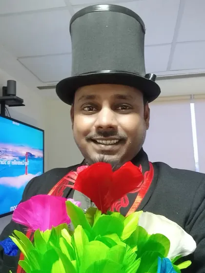 Hello. I’m Somu, and I’m ready to bring some fun and wonder to your next party. This is me with one of my favorite props, the feather flower bouquet, which always adds a splash of color to my act.