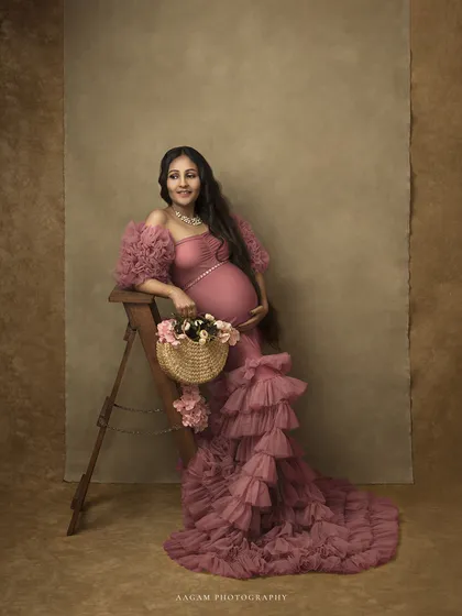 Dressed in a stunning pink ruffled gown, this mother-to-be looks like she stepped out of a fairytale. The basket of flowers adds a charming, rustic touch.
