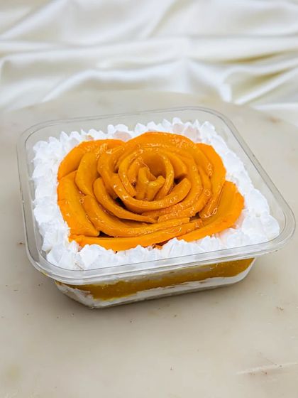 Our Mango Fresh Cream cake is also available in a tub. It's layered with our signature vanilla sponge, light cream, homemade aamras, and diced mangoes for a perfect summer treat.