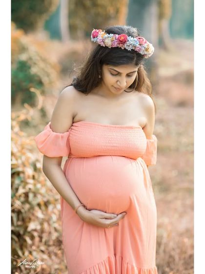 A gentle and introspective pose. Here, the mother-to-be looks down at her bump, capturing a personal and quiet moment of connection with her baby.