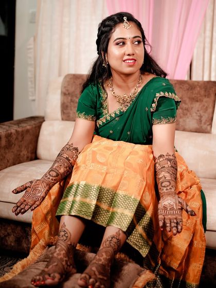 A full shot of the bride, seated, showing her complete hand and feet mehendi. She looks absolutely ready for her big day.