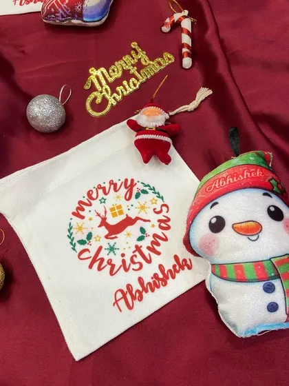 A personalised snowman plush ornament and matching goodie bag for 'Abhishek'.