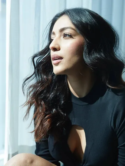 Keeping it simple and chic with Sahher Bambba. This black cutout top paired with jeans is a great example of a stylish, minimalist look for a casual photoshoot or appearance.