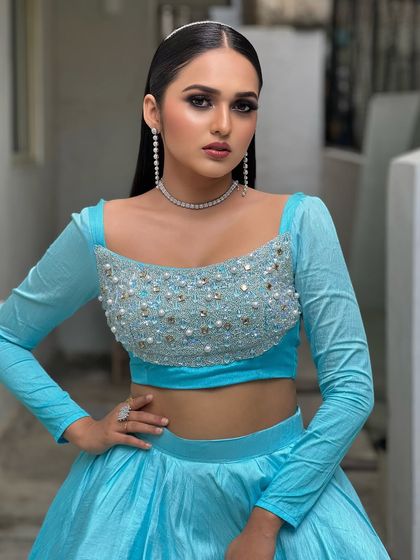 A bold and high-fashion look in a bright blue lehenga. The makeup is dramatic, with a sharp winged liner and a sleek, wet-look hairstyle.