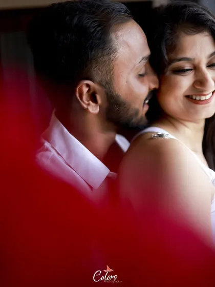 A close-up shot with a creative foreground element, focusing on the couple's happy and intimate whisper.