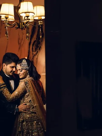 An intimate embrace in a warmly lit room. This portrait has a classic, old-world romance feel, with the chandelier adding a touch of elegance.