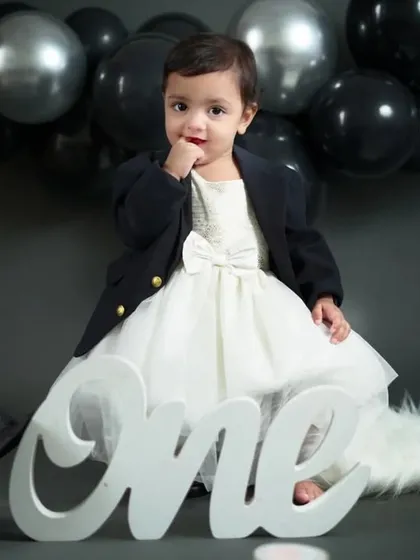 A classic portrait for a first birthday. This little girl looks so chic and adorable in her white dress and black jacket, ready to celebrate turning one.