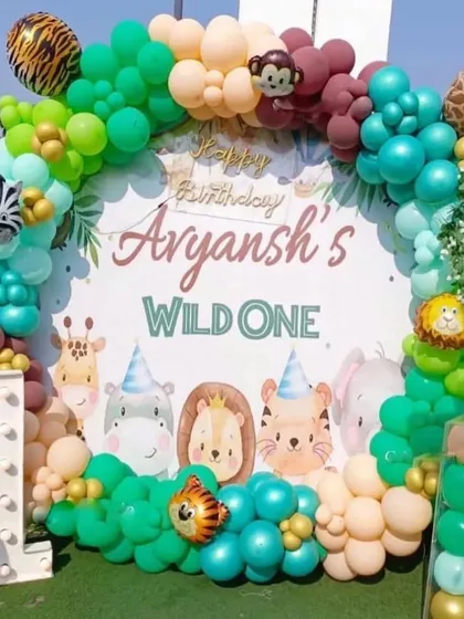 A "Wild One" first birthday party with a circular backdrop. This outdoor setup includes a balloon arch with animal print accents and cute animal characters.