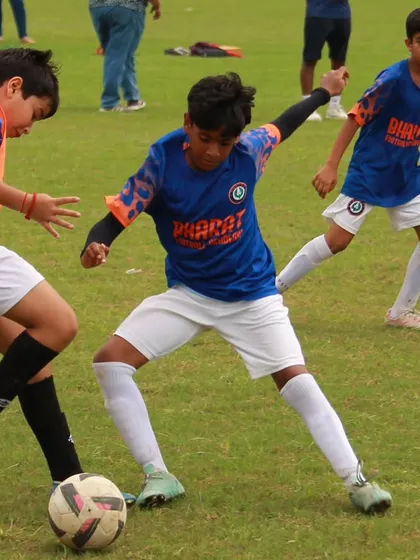 Passion, hustle, and teamwork. A young player skillfully shields the ball from two opponents, showing great strength and ball control.