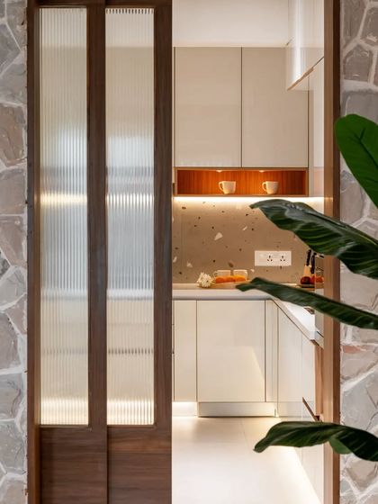 A peek into the bright and happy kitchen from the stone-clad hallway. I used fluted glass on the sliding door to allow light to pass through while still providing a sense of separation.