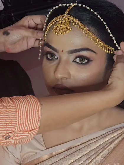 A behind-the-scenes shot of me placing the nethi chutti on a model for a traditional bridal look.