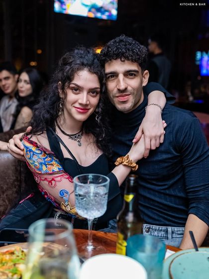 A couple enjoying a meal and drinks at their table.