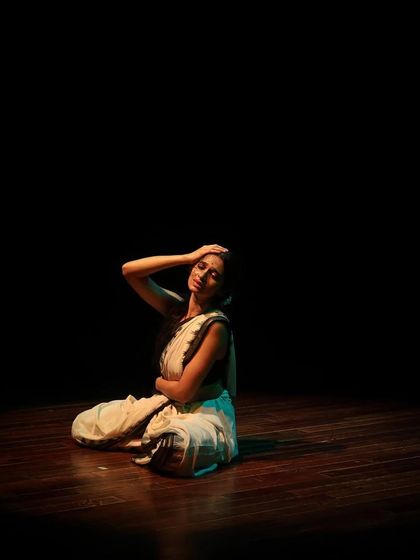 A Bharatanatyam dancer in a moment of quiet expression during "Parabola of Dance." The event features post-performance conversations with the artists about their choreographic journeys.