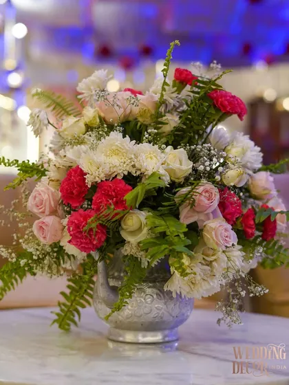 A beautiful centerpiece of pink and white flowers in an ornate silver vase. This classic arrangement adds a touch of elegance and romance to the guest tables.