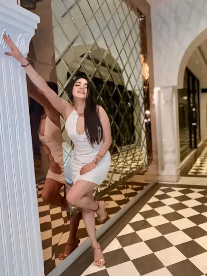 A full-length shot against a checkered floor and mirrored wall, creating a visually dynamic and interesting composition.