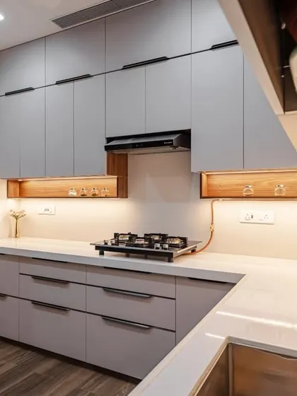 A premium C-shaped modular kitchen at Kohinoor Square, Dadar. The light grey cabinets are paired with wooden open shelves, creating a modern yet warm aesthetic. The design is optimized for an easy workflow.