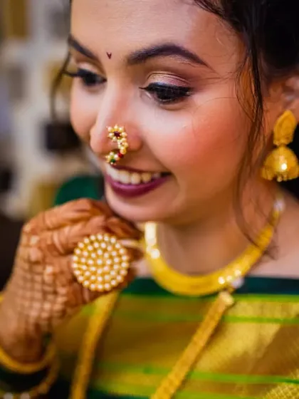 A close-up shot showcasing the details of the bride's makeup and jewelry. The traditional Maharashtrian nath and the delicate bindi are key elements of her engagement look.
