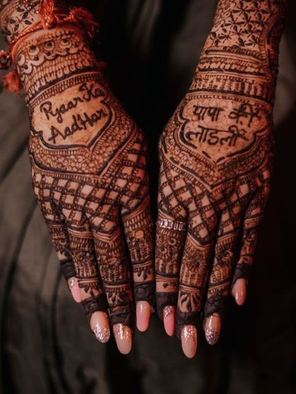 The dark stain of the henna makes the personalized text stand out beautifully against the intricate background design.