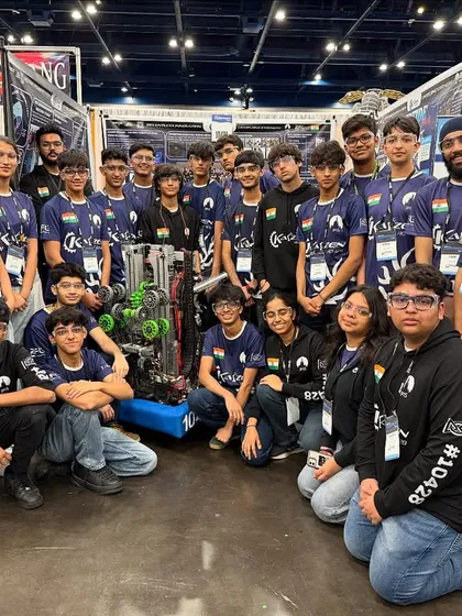 The full Team Kaizen with their mentors and robot at the World Championship pit area. It shows the entire support system behind their success.