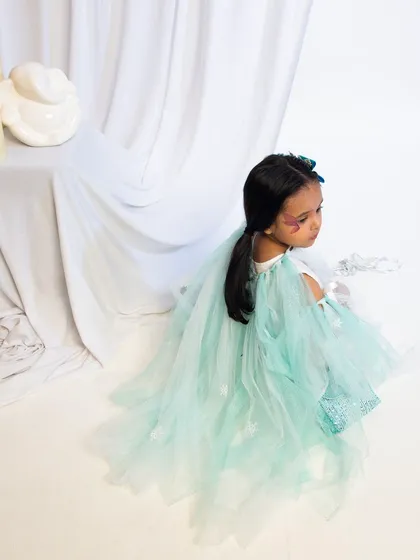 A high-angle shot of a child in a beautiful light-green fairy costume.