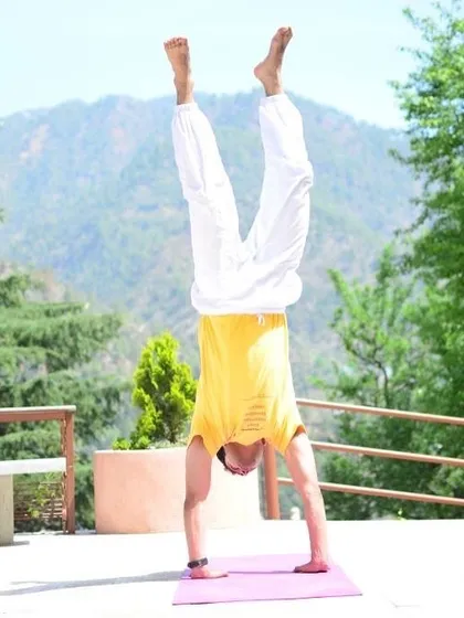 A student demonstrates strength and balance in a handstand against the stunning backdrop of the Himalayas. The clean mountain air and serene environment empower you to explore your potential.