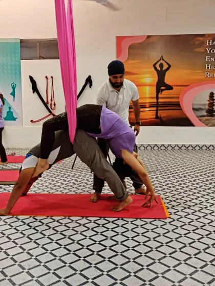 I am providing hands-on guidance during an aerial Acro Yoga pose to ensure correct alignment and safety. My focus is always on supporting my students' progress.