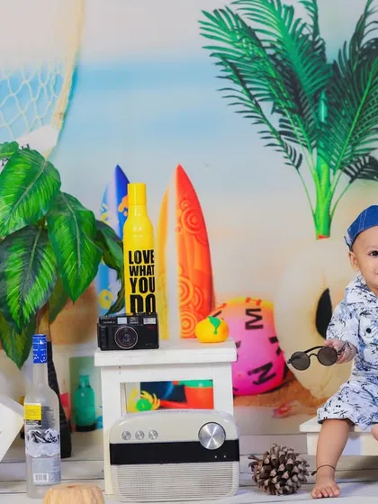 A playful moment as the baby takes off his sunglasses, smiling and enjoying the beachy atmosphere of our studio.