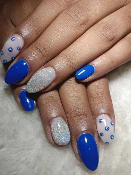 A fun mix of styles. This set includes bold cobalt blue, holographic silver glitter, and a nude accent nail with a hand-painted evil eye pattern.