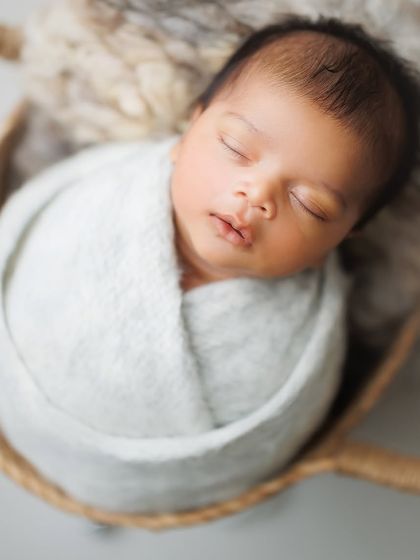 A simple close-up allows all the focus to be on the baby's perfect features. The soft texture of the light blue wrap adds just enough detail to this serene portrait.