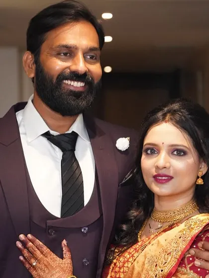 My beautiful client with her partner, ready for a wedding reception. Her makeup is soft and elegant, paired with a traditional red saree.