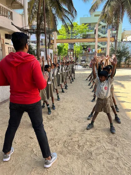 Students in their school uniforms participate in an outdoor drill session. These synchronized movements are key for warming up the body and developing discipline and focus before we begin our games.
