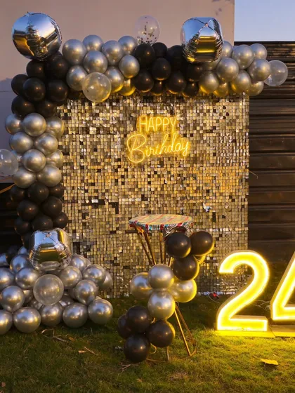 A clear, well-lit photo of the silver and black 24th birthday backdrop.
