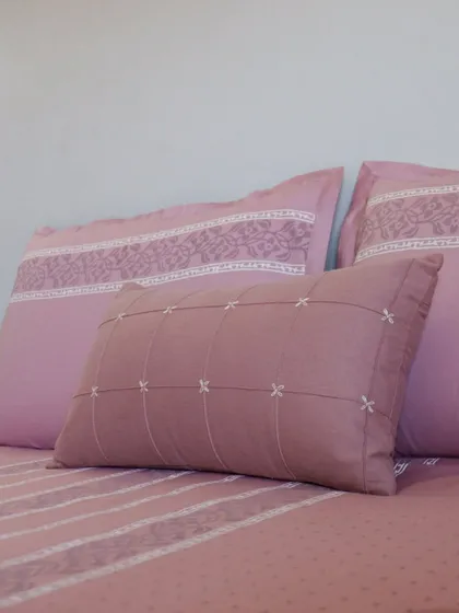 A closer look at the textured accent cushion and pillowcases from our blush pink bedding set. The pintucked details and fine embroidery showcase our commitment to creating pieces with subtle, sophisticated charm.