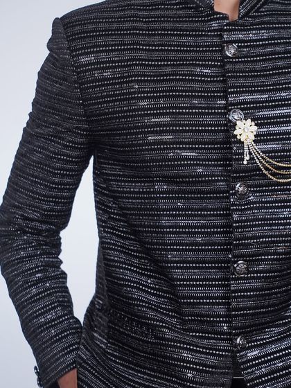 A close-up of the black striped bandhgala jacket, focusing on the shimmering fabric and the elegant brooch detail.