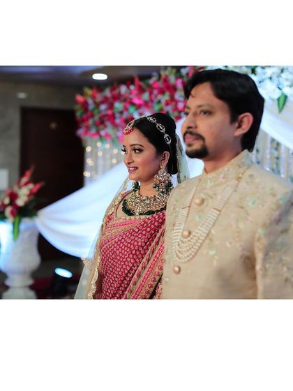The happy couple, ready for their reception. The bride's makeup is coordinated with her red lehenga, creating a cohesive and stunning look.