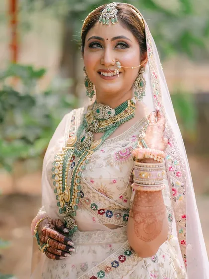 A stunning close-up of the bride. Her eyes are beautifully defined, and the green jewelry adds a perfect pop of color to her soft, elegant look.