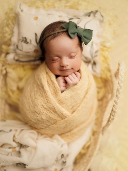 A close-up of this sweet baby girl, showing off her peaceful smile and the adorable green bow. These are the details you'll want to remember forever.