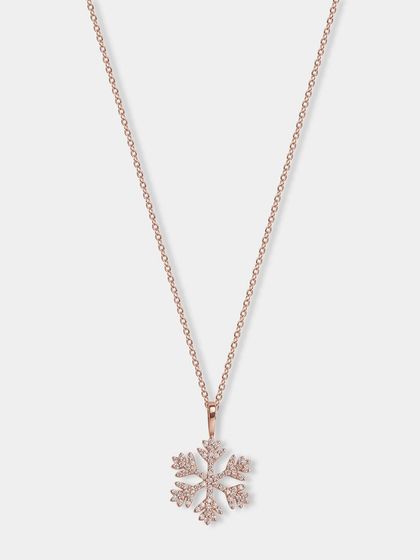 A delicate rose gold snowflake pendant necklace. The lighting is carefully controlled to make the small crystals sparkle.