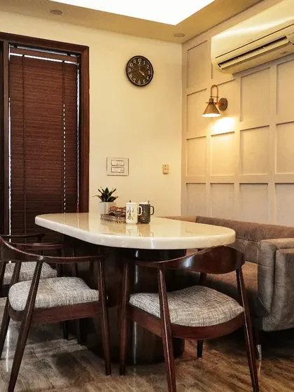 A wider view of the dining area, showing the custom-built seating, marble-top table, and its proximity to the kitchen, making it a practical and stylish family hub.