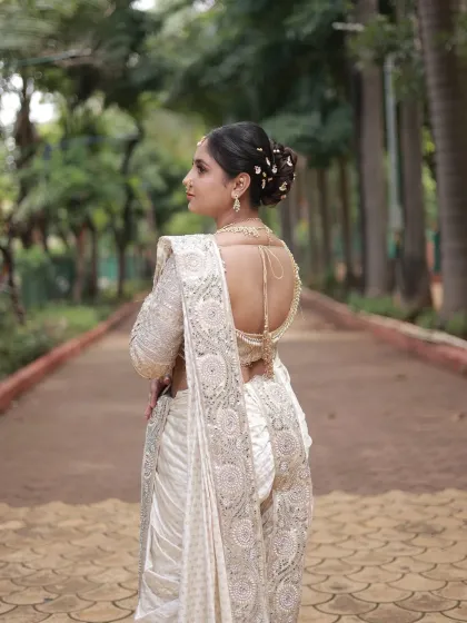 The back view of the Nauvari look, highlighting the beautiful low back blouse design and the traditional bun hairstyle adorned with hair accessories.