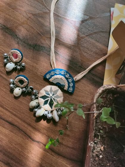 This handcrafted mirror work necklace set is made with a combination of fabric, thread work, and cowrie shells. The design is inspired by traditional Gujarati jewelry, perfect for garba nights.