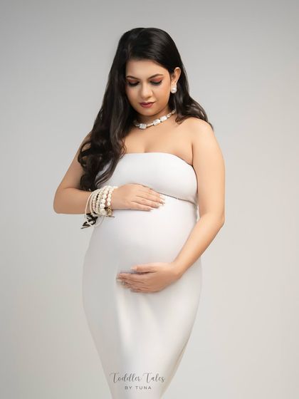 A quiet moment of connection. Without the hat, the focus shifts to the mother's gentle expression as she looks down at her bump, her hands cradling it lovingly.