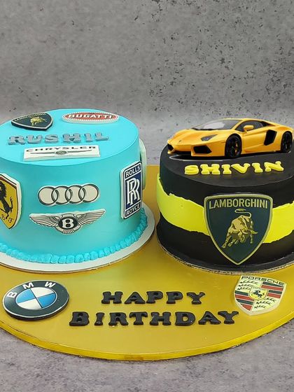A set of two car-themed cakes for brothers. One features various luxury car logos, while the other is a Lamborghini-themed cake with a 3D car topper.