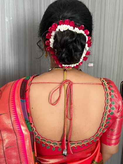 A detailed view of the simple hair bun, beautifully decorated with a string of real red and white flowers for a traditional touch.