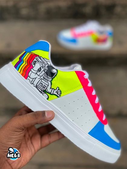 A hand-held shot of the astronaut side of our custom Campus shoes. The design features a thumbs-up astronaut with a rainbow trail.