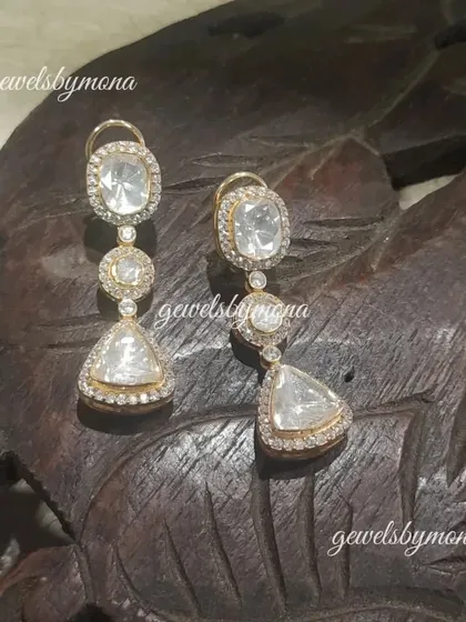 A pair of modern polki earrings featuring different geometric shapes. The combination of round, oval, and triangular polki stones creates a unique and contemporary design.