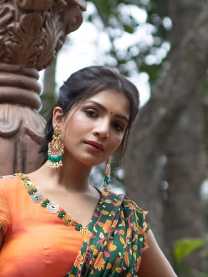 A portrait showcasing the detailed embroidery on the blouse of an orange pleated lehenga, a vibrant choice for any festivity.