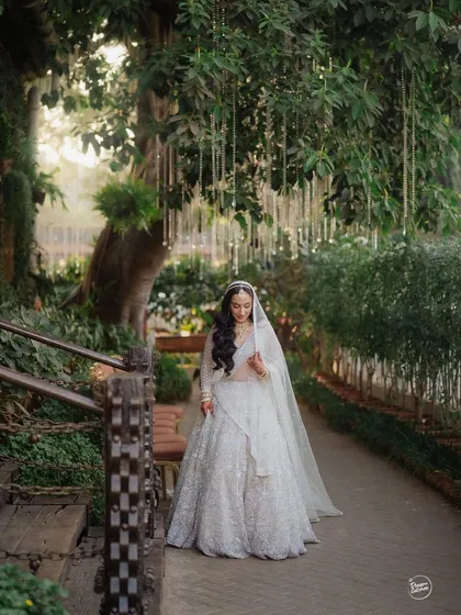 A beautiful shot of the bride walking along a garden path, her veil trailing behind her, creating a sense of movement and grace.